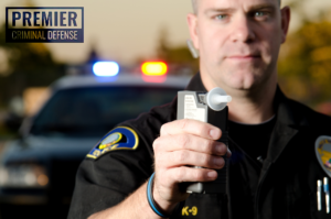 Police officer holding handheld DUI breathalyzer test machine